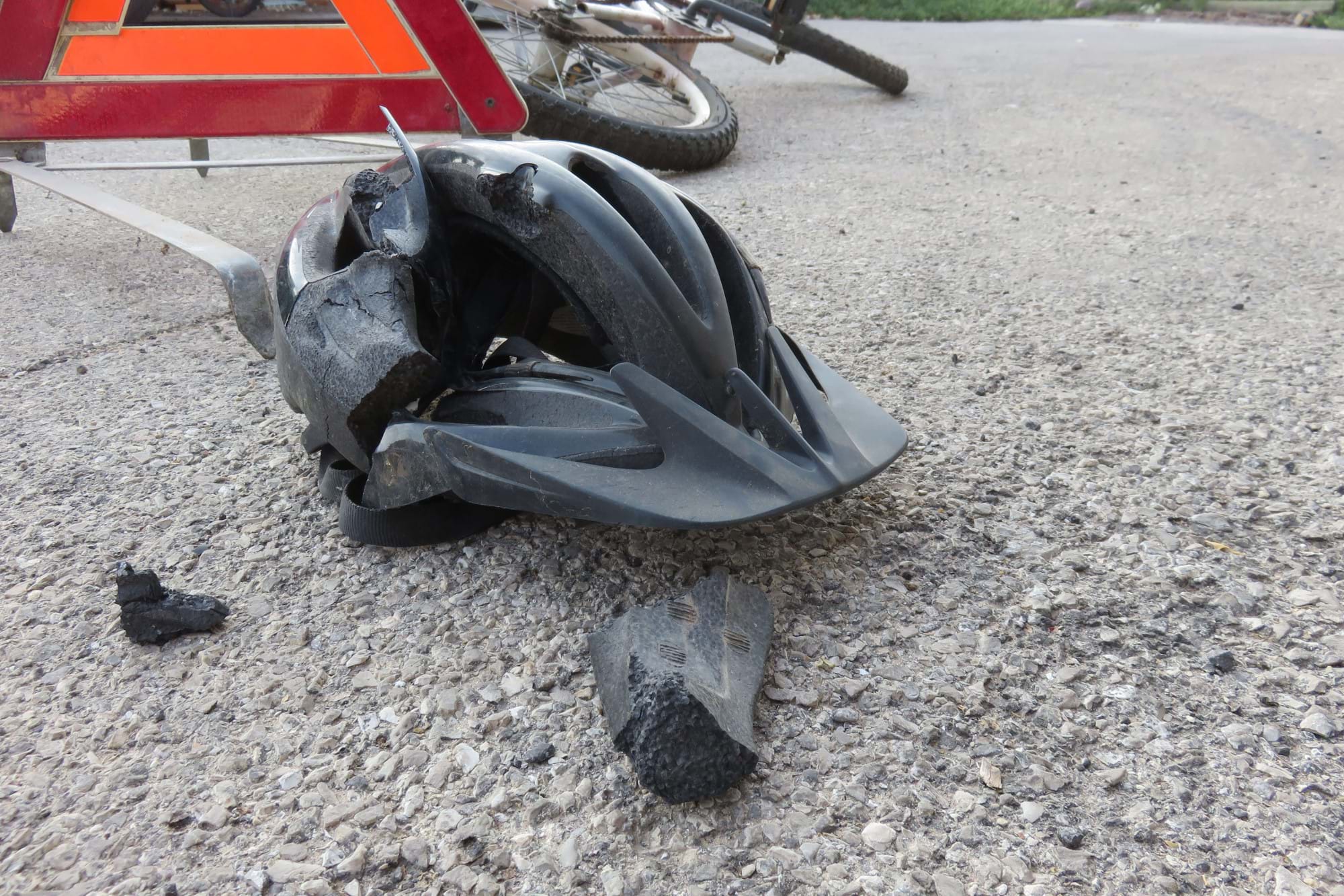 A bicycle helmet crushed on the road following a road traffic accident