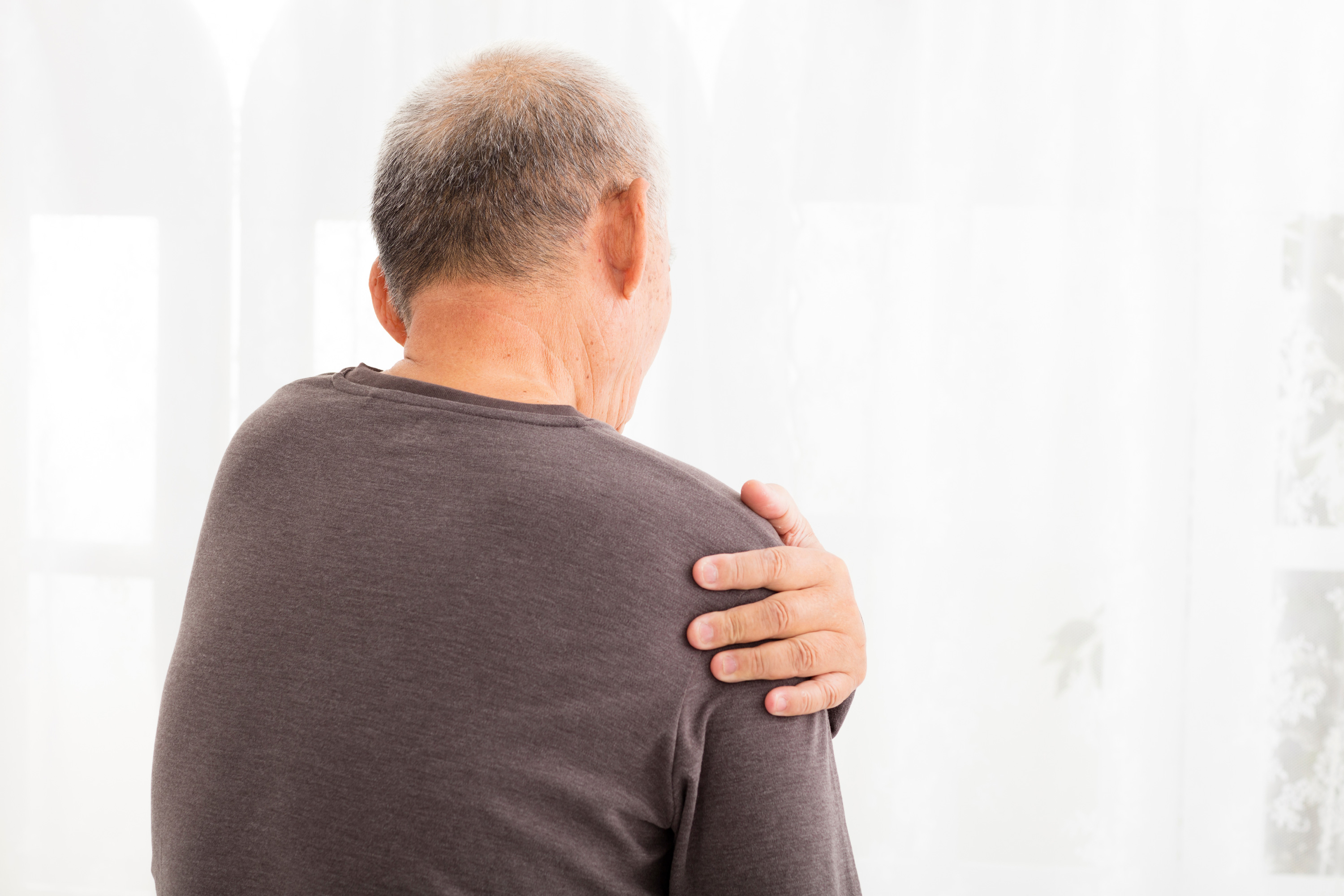 An older, balding man feels his shoulder in pain after an accident at work.