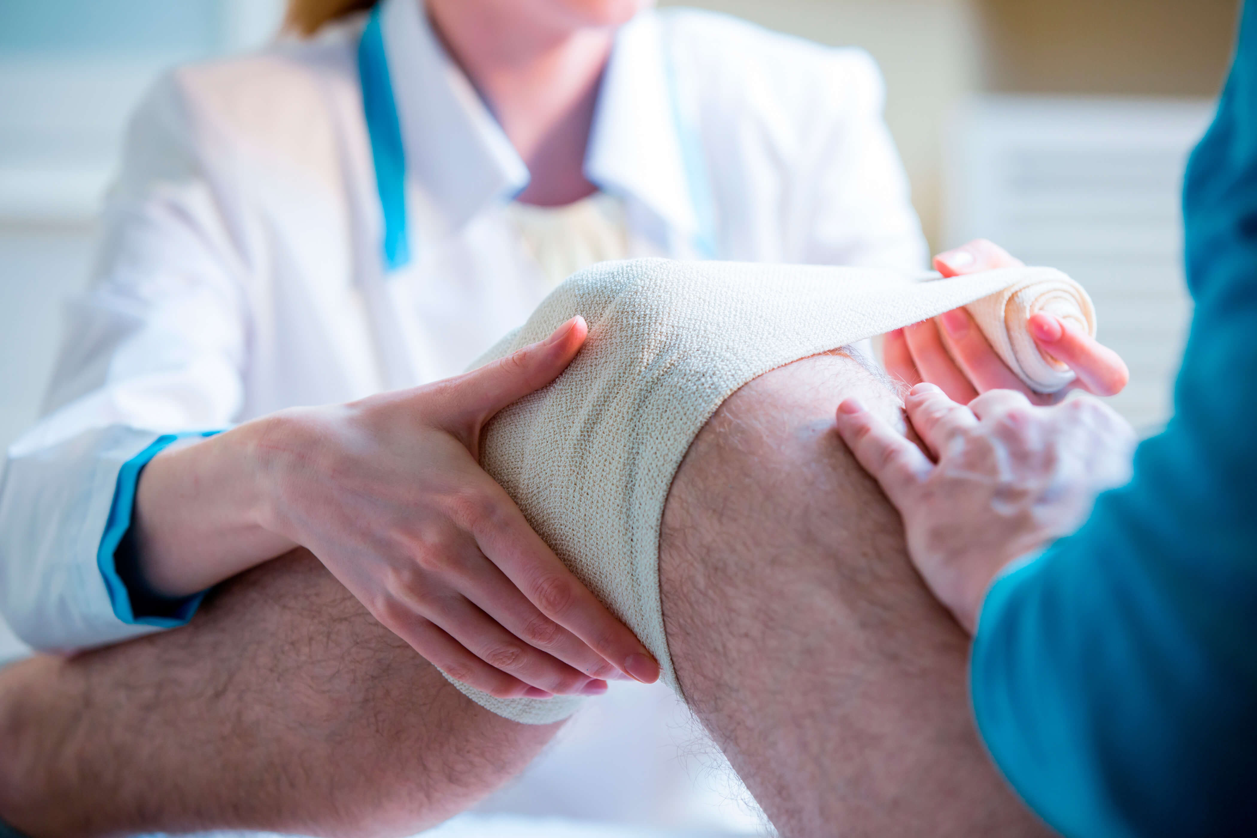 A man has his knee bandaged up by a nurse after an accident at work