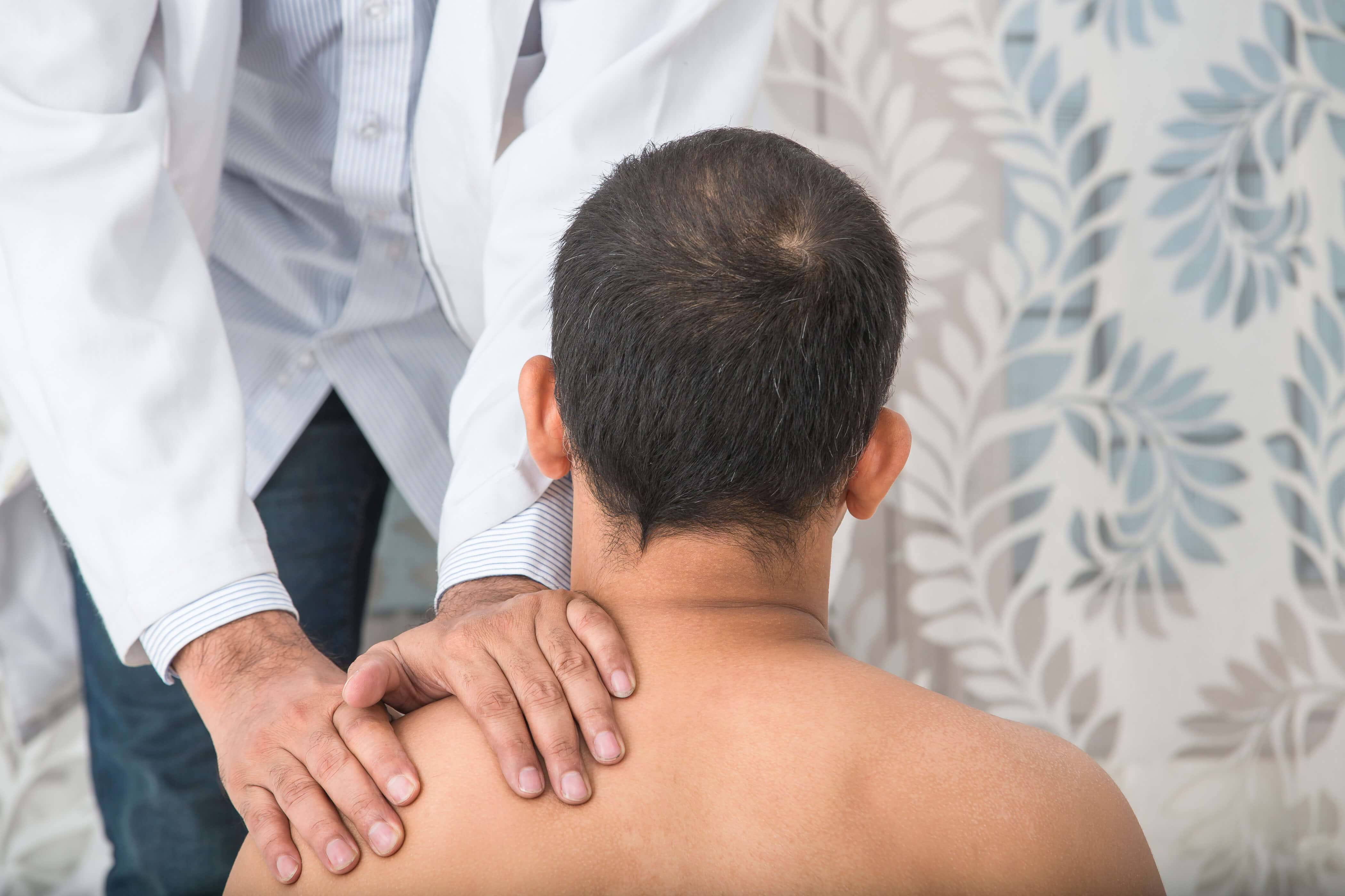 A man receives shoulder treatment from a doctor after an accident at work 