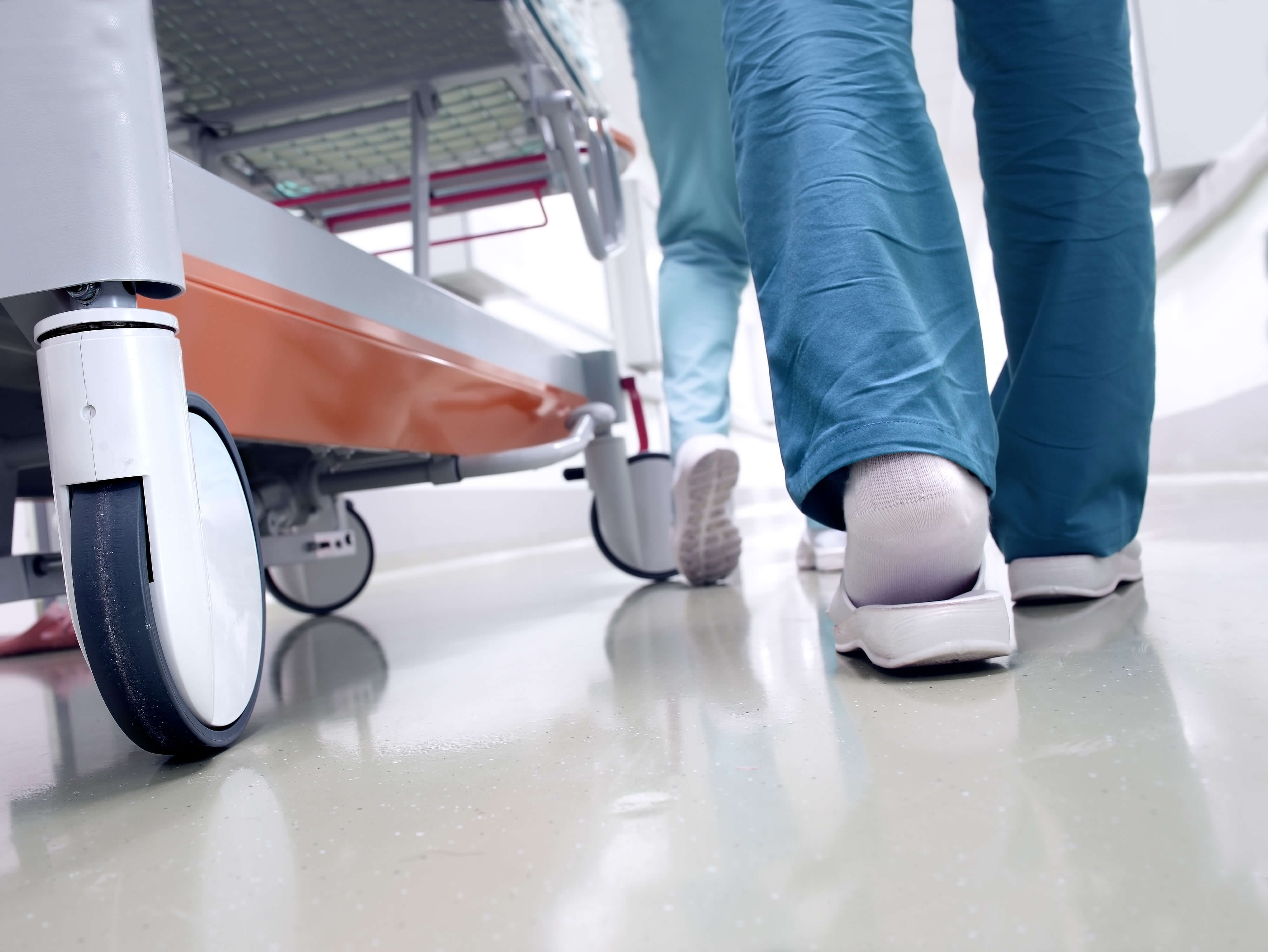 A patient trolley being pushed by a member of staff through a hospital