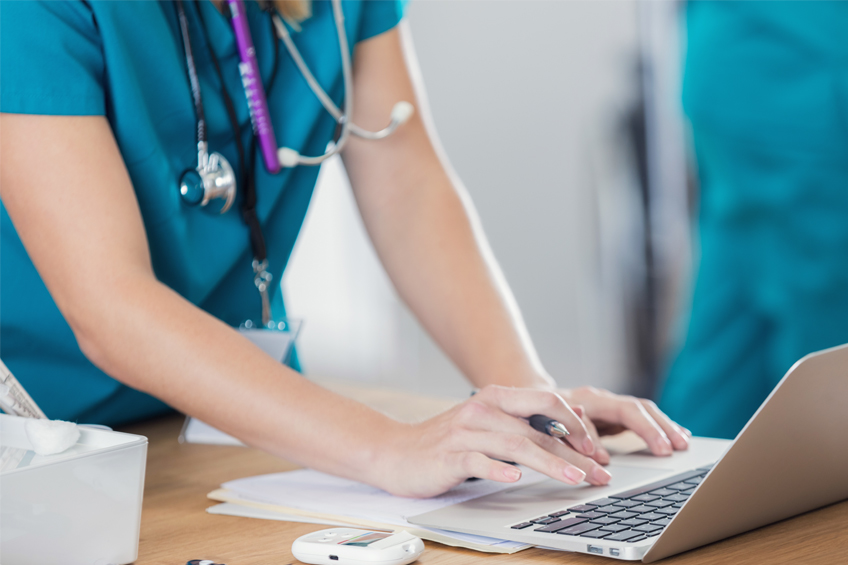 A midwife works at a laptop on a desk in a hospital