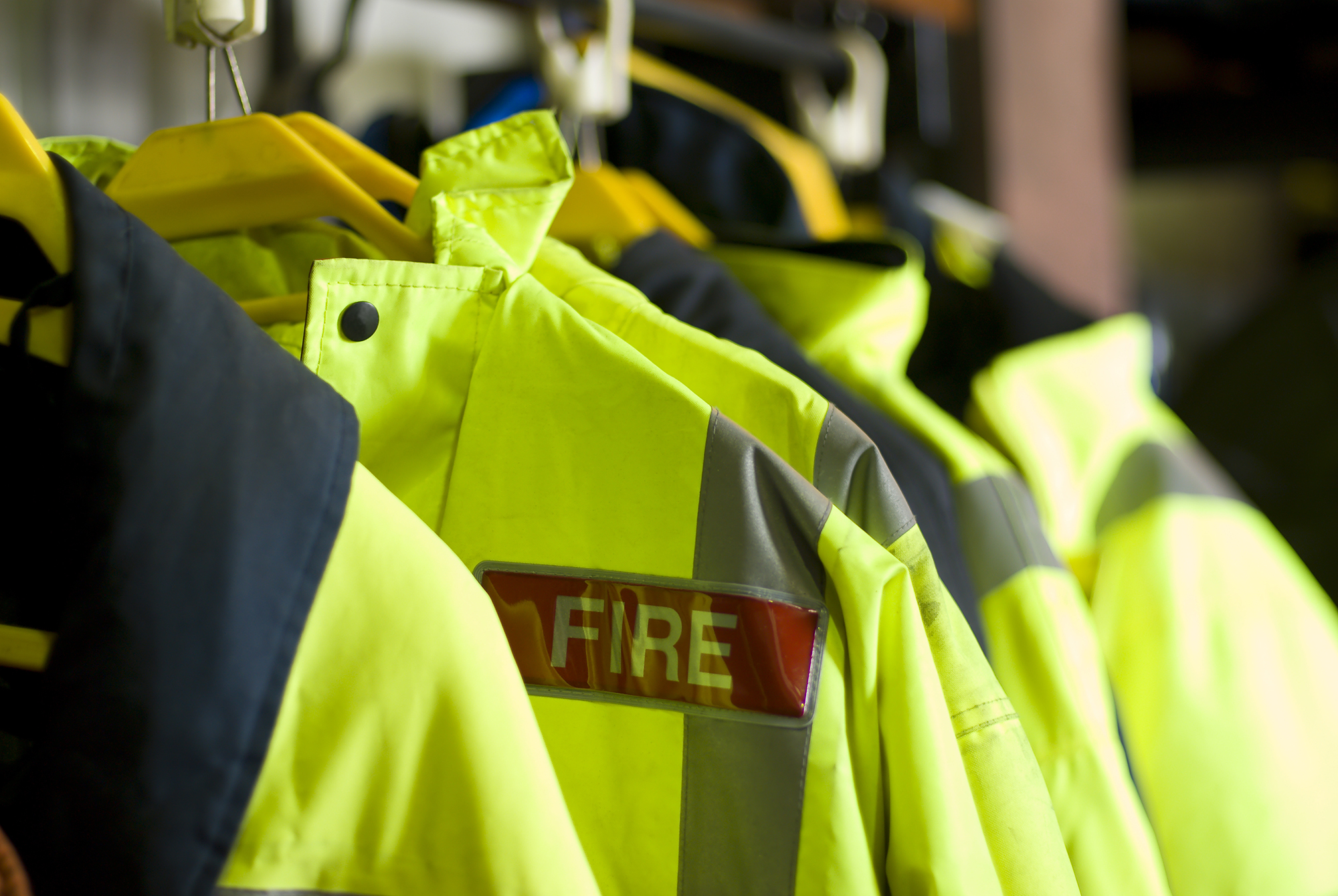 A row of Firefighter uniforms hanging from coathangers 