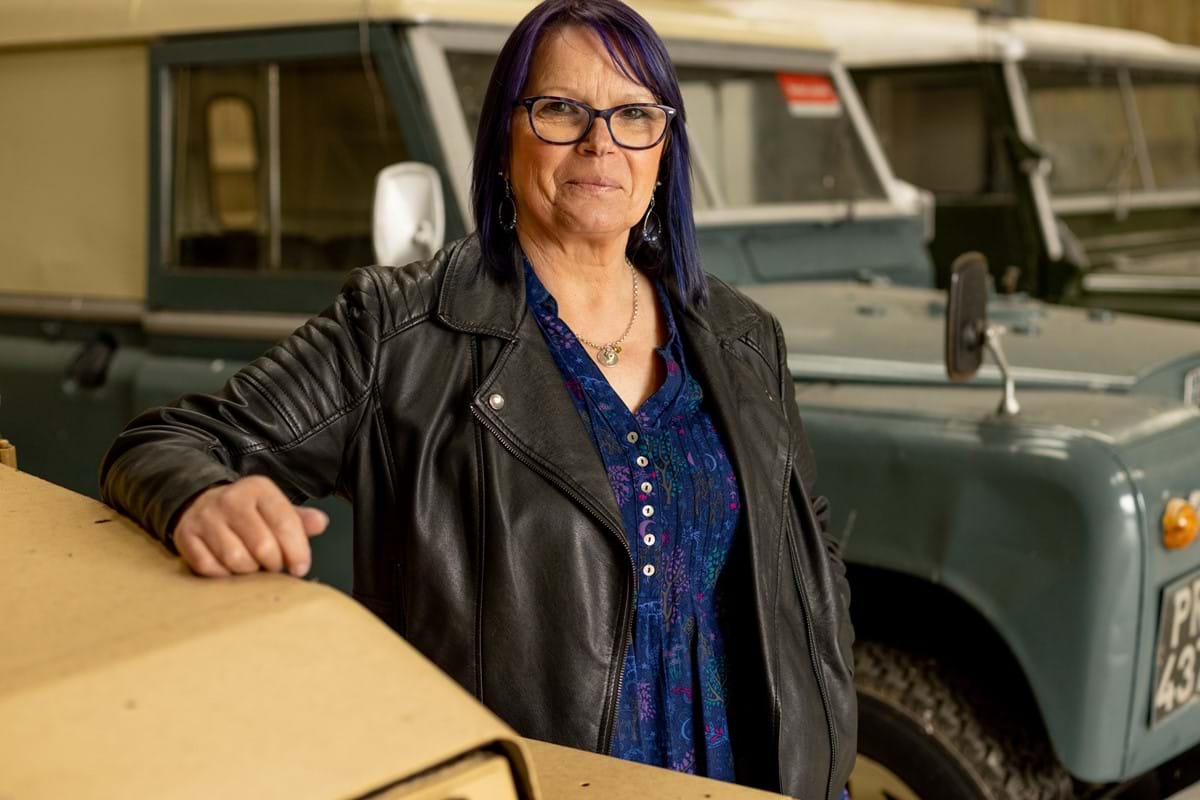 An image of a woman stood by a landrover