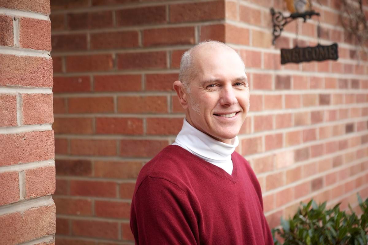 Robert Warren pictured in a red jumper outside his house, smiling