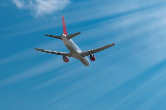 A white and orange airplane is photographed from beneath against a clear blue sky